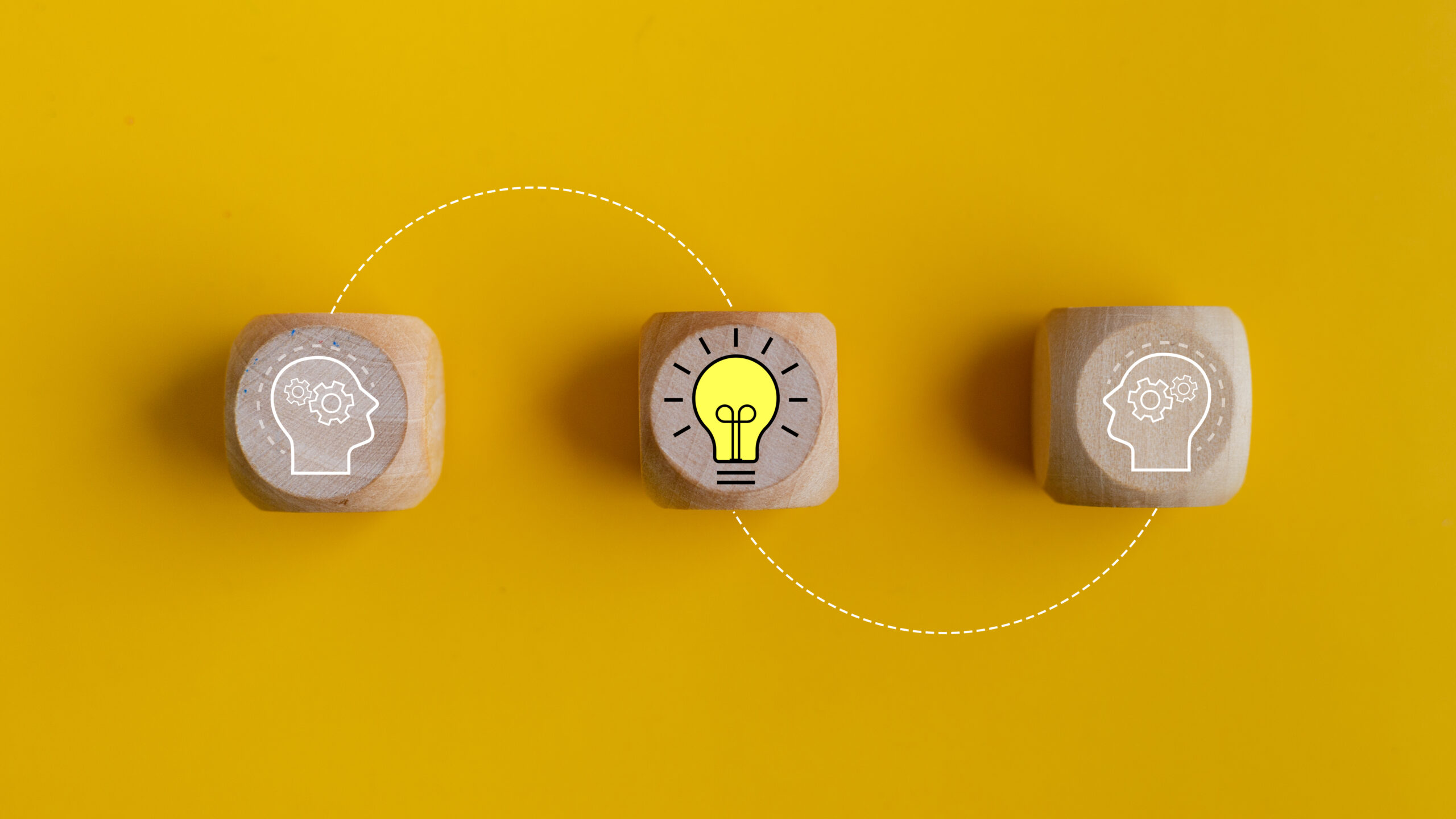 Creative idea and innovation concept. Wooden blocks with lightbulb and human head on yellow background