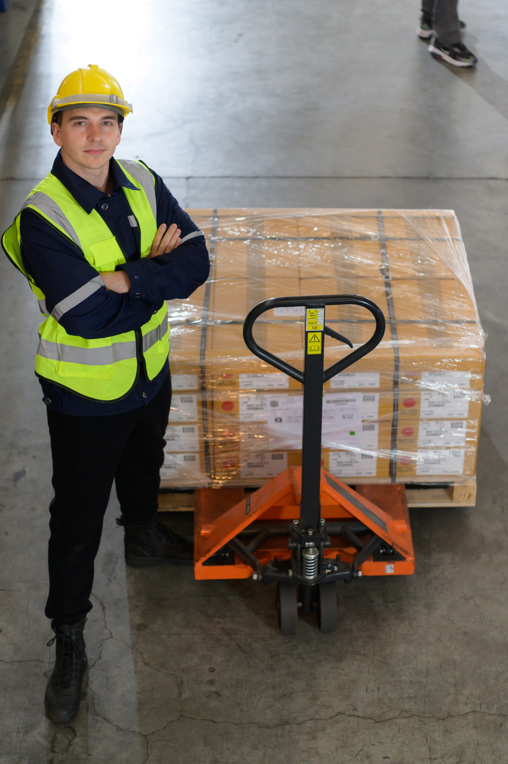Worker use a handcart to work to bring the box of parts into the storage shelf of the warehouse